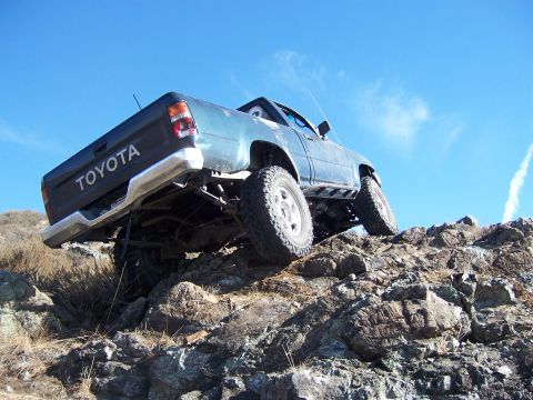 1995 Toyota Hilux - This 1995 Toyota Hilux is shown navigating a challenging rocky incline under a clear blue sky.