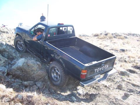 1995 Toyota Hilux - Toyota pickup truck navigating a rocky off-road course with a driver at the wheel.