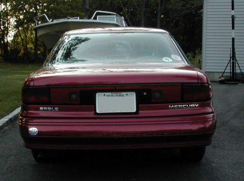 1995 Mercury Sable - Rear view of a red 1995 Mercury Sable sedan, showing the taillights, "SABLE" and "MERCURY" badging, and a New York license plate.