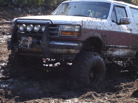 1989 Ford Bronco - Muddy 1989 Ford Bronco navigating difficult terrain off-road.
