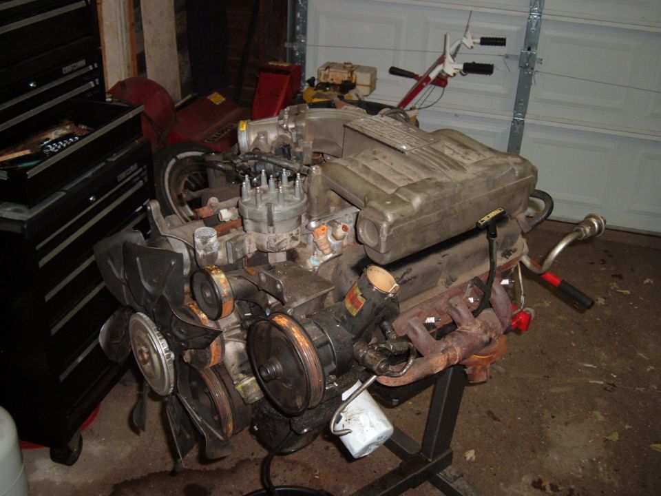 Disassembled V8 engine sitting on an engine stand in a garage