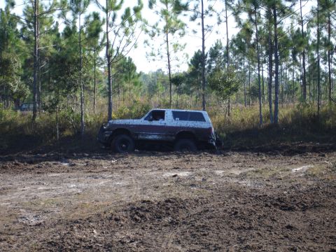 1989 Ford Bronco - Ford Bronco is stuck in the mud with trees in the background.