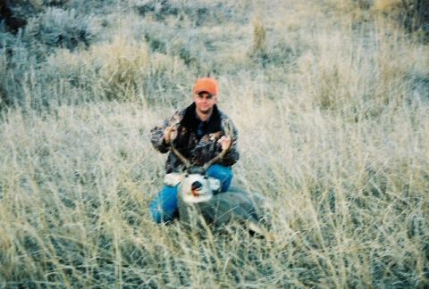 1996 Ford Bronco - A hunter poses with a deer he has harvested in a field of dry grass.