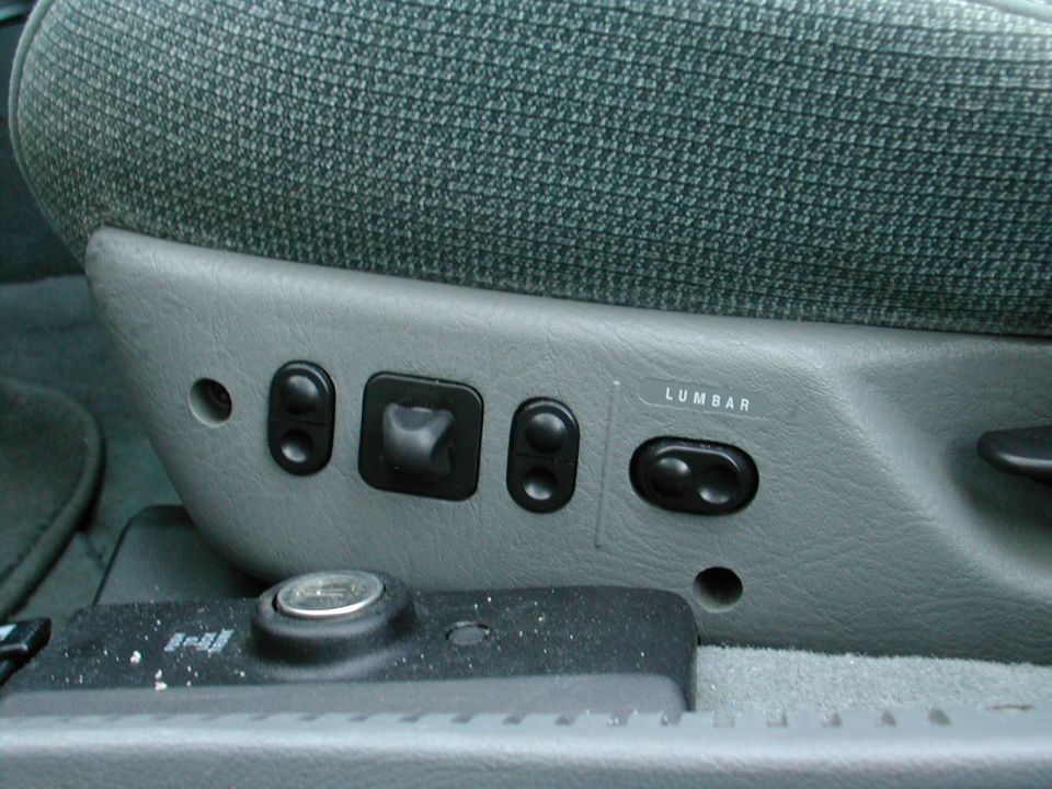 Gray car seat side panel with black power adjustment switches and LUMBAR label
