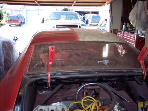1971 Ford Mustang - The open trunk of a red car reveals its interior and rear window, with other vehicles visible in the background.