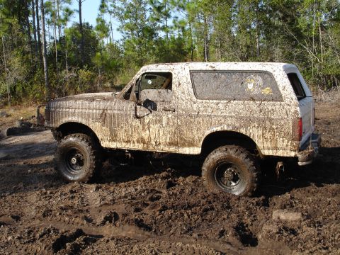 1989 Ford Bronco - Mud-covered 1989 Ford Bronco stuck in a muddy off-road environment.