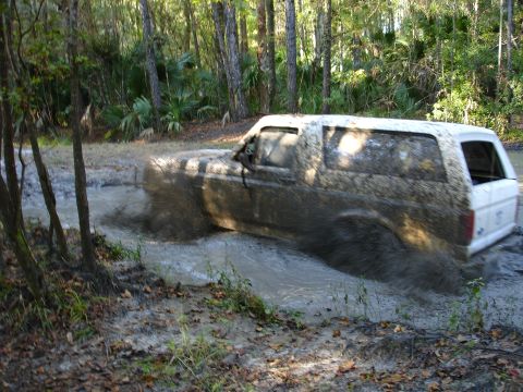 1989 Ford Bronco - Muddy 1989 Ford Bronco navigating a difficult off-road path.