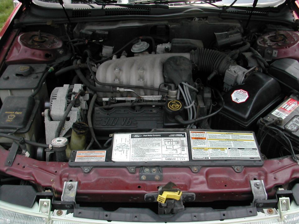Engine bay with Ford 3.0 V6 engine in a maroon 1995 Mercury Sable, emission decal on radiator support