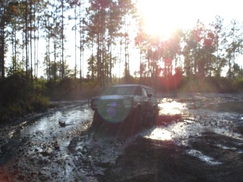 1989 Ford Bronco - Ford Bronco navigating a challenging muddy terrain under bright sunlight.
