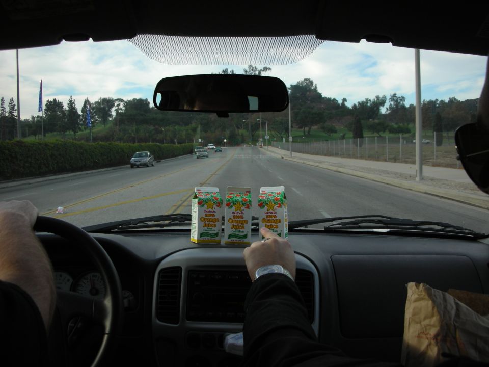 Driver's view through a windshield of a road with juice cartons on the dash