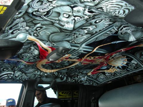 1998 Ford Crown Victoria - custom vehicle interior headliner airbrushed with grayscale skulls and a colorful red-and-gold dragon, with occupants visible below.