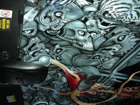1998 Ford Crown Victoria - vehicle interior panel airbrushed with skull artwork next to a black armrest and an air bag warning sticker.