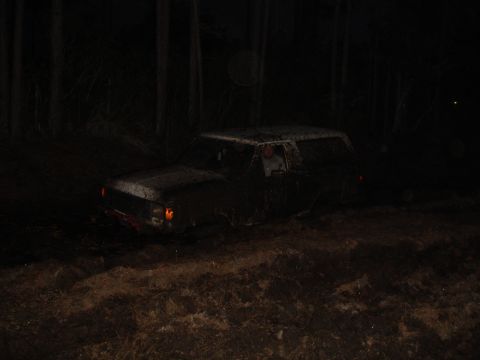 1989 Ford Bronco - A muddy SUV navigates through dark, wooded terrain at night.