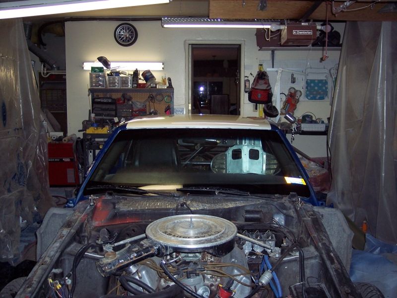 Car interior and engine bay with blue exterior paint, white roof, and exposed engine components