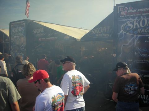 1998 Ford Crown Victoria - crowd of spectators gathers in smoky air near black Skoal Racing trackside tents flying an American flag.