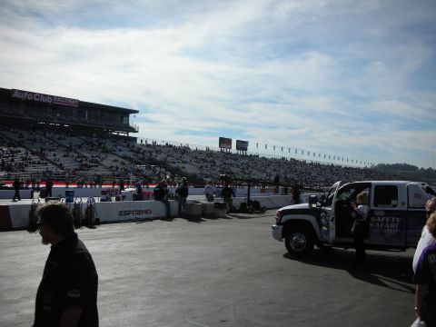 1998 Ford Crown Victoria - white pickup marked Safety Safari sits on the dragstrip apron at Auto Club Raceway with crowded grandstands behind.