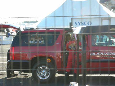 1998 Ford Crown Victoria - red Budweiser Racing SUV parked in the pits with a driver in a matching red firesuit standing at the open door.