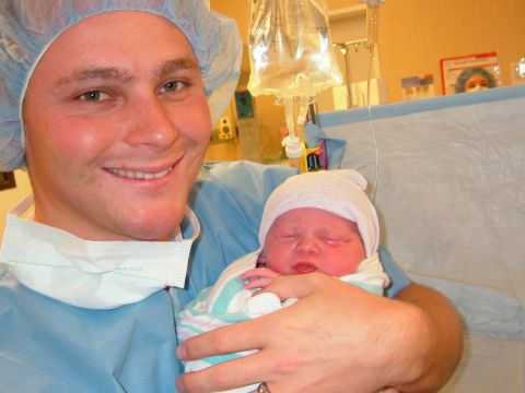 1996 Ford Bronco - A person in medical scrubs smiles while holding a newborn baby in a hospital setting.