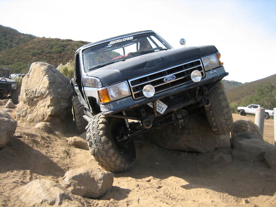 Black Ford F-Series truck with off-road tires navigating rocks