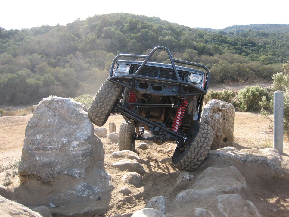 Off-road vehicle with a roll cage climbing over large rocks on a trail