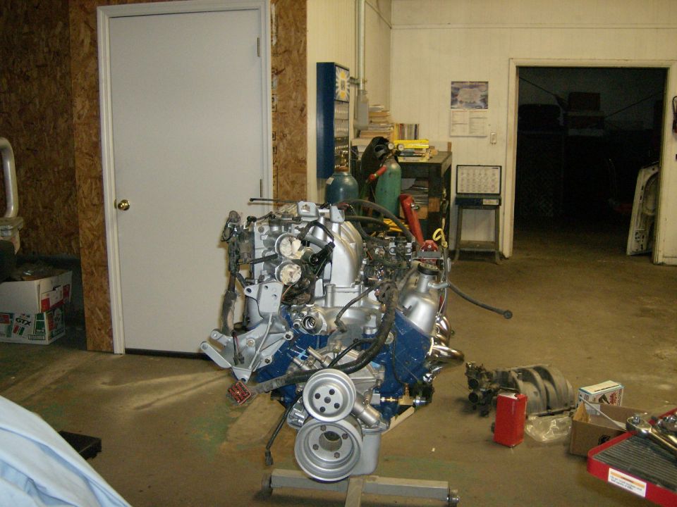 Blue and silver V8 engine on a stand in a garage workshop