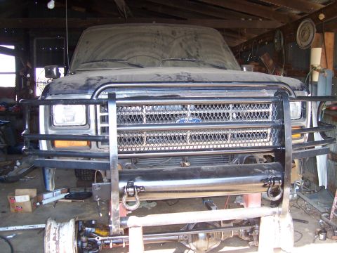 1983 Ford Bronco - Front view of a dusty dark blue Ford Bronco with a brush guard, parked indoors.