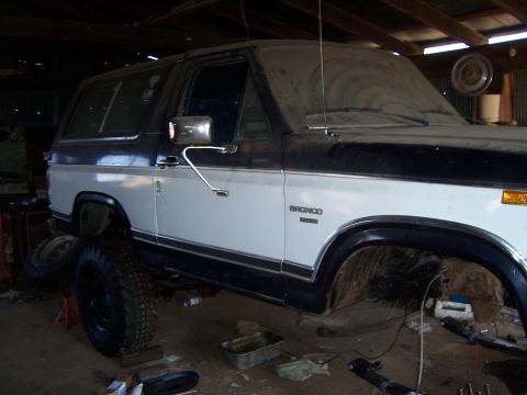 1983 Ford Bronco - This two-tone 1983 Ford Bronco is shown in a garage, appearing to be undergoing maintenance or restoration.
