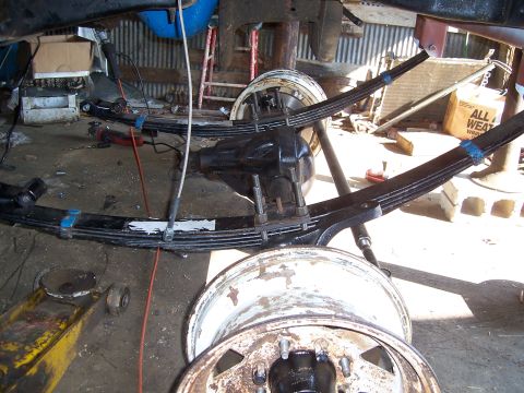 1983 Ford Bronco - Close-up view of the rear axle and leaf spring suspension system, likely undergoing maintenance or repair.