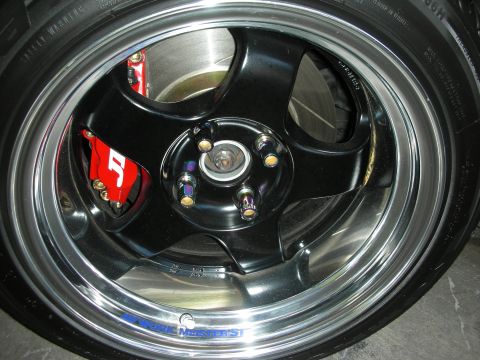 1998 Ford Crown Victoria - close-up of a black five-spoke alloy wheel with a polished lip, exposed hub, and a red brake caliper.