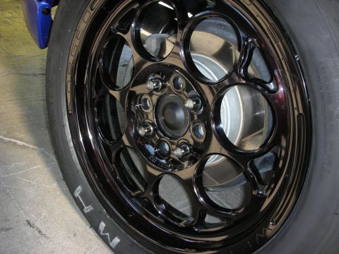 1998 Ford Crown Victoria - close-up of a glossy black multi-spoke drag-style wheel mounted on an M/T tire with a blue brake caliper.