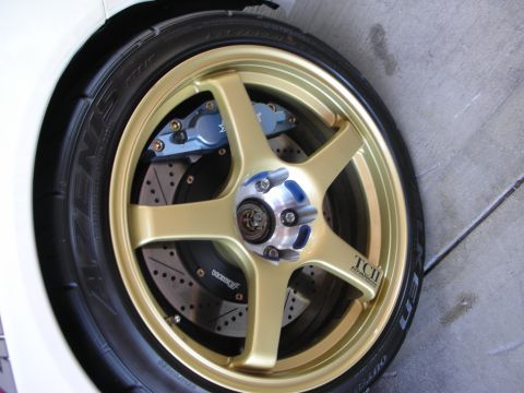 1998 Ford Crown Victoria - close-up of a gold five-spoke wheel with a blue brake caliper, cross-drilled slotted rotor, and a Falken Azenis tire.
