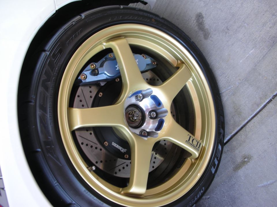 Gold five-spoke wheel with blue caliper, drilled rotor, Azenis tire