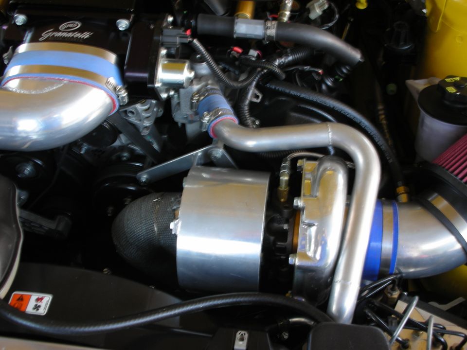 Close-up of polished supercharger and intercooler piping in engine bay