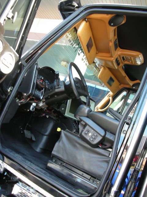 1998 Ford Crown Victoria - Interior of a black SUV viewed through the open door, showing a tan dashboard, steering wheel, and console.