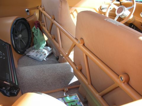1998 Ford Crown Victoria - Custom interior in tan upholstery showing a subwoofer enclosure, tubular brace, and bench seat detail.