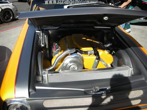 1998 Ford Crown Victoria - Open rear deck of an orange-and-gray custom car revealing a rear-mounted turbocharged engine and intercooler.