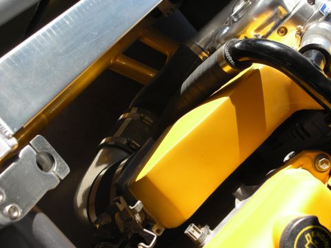 1998 Ford Crown Victoria - Detail of a yellow-painted engine component with a black hose, braided line, and aluminum bracket.