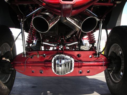 1998 Ford Crown Victoria - Underside rear view of a lifted truck showing a chrome diff cover, red axle housing, twin coilovers, and two chrome exhaust tips.