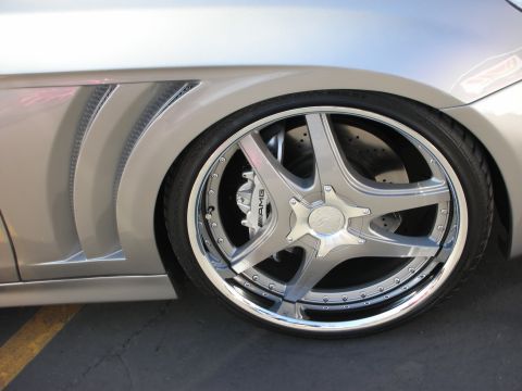 1998 Ford Crown Victoria - Close-up of a polished chrome AMG five-spoke wheel with drilled brake rotor on a silver Mercedes-Benz.