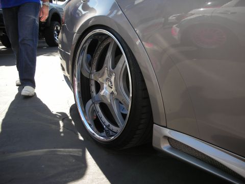 1998 Ford Crown Victoria - low-profile stretched tire on a polished chrome multi-spoke wheel under the flared fender of a slammed silver car.