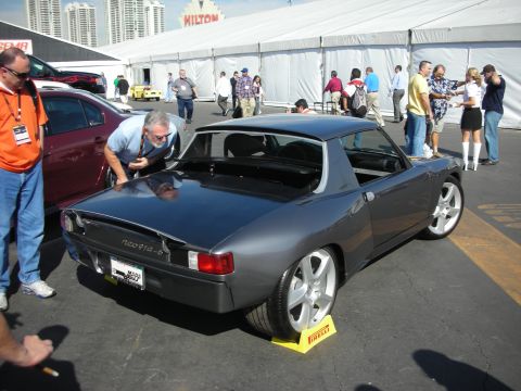 1998 Ford Crown Victoria - gray custom two-door sports coupe seen from the rear three-quarter at an outdoor show with onlookers near a Hilton sign.