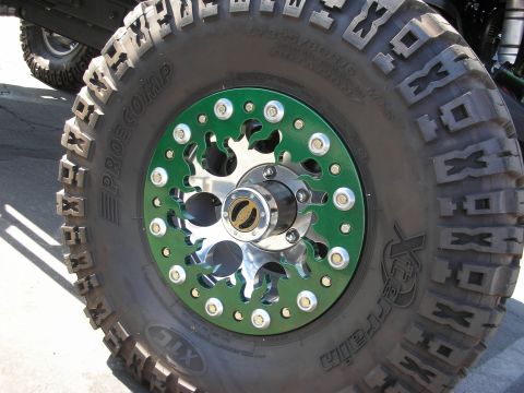 1998 Ford Crown Victoria - polished wheel with green beadlock ring wrapped in a chunky Pro Comp Xtreme mud-terrain off-road tire.