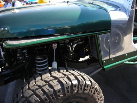 1998 Ford Crown Victoria - Close view of a green custom vehicle's front fender, aluminum panels, coilover shock, and mud tire at a show.
