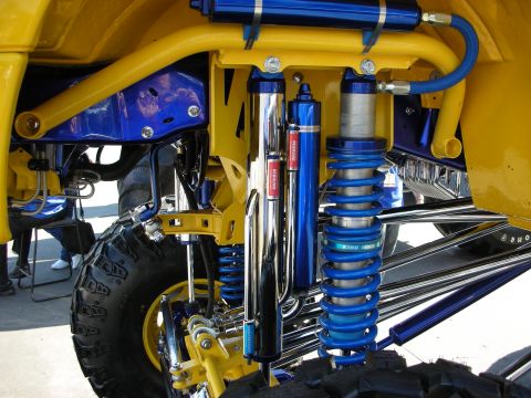 1998 Ford Crown Victoria - Close-up of a yellow vehicle's blue suspension with a blue King coilover, chrome bypass shock, and traction bars.