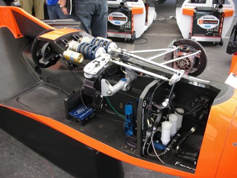 1998 Ford Crown Victoria - Detail of an orange open-wheel race car's cockpit and rear bay with coilover, Ford components, and radiator plumbing.