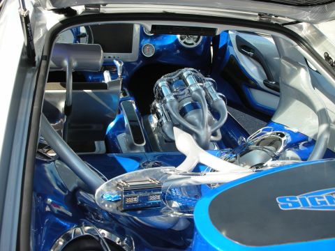 1998 Ford Crown Victoria - heavily customized car shows a chrome supercharged engine and digital gauges built into a bright blue interior.