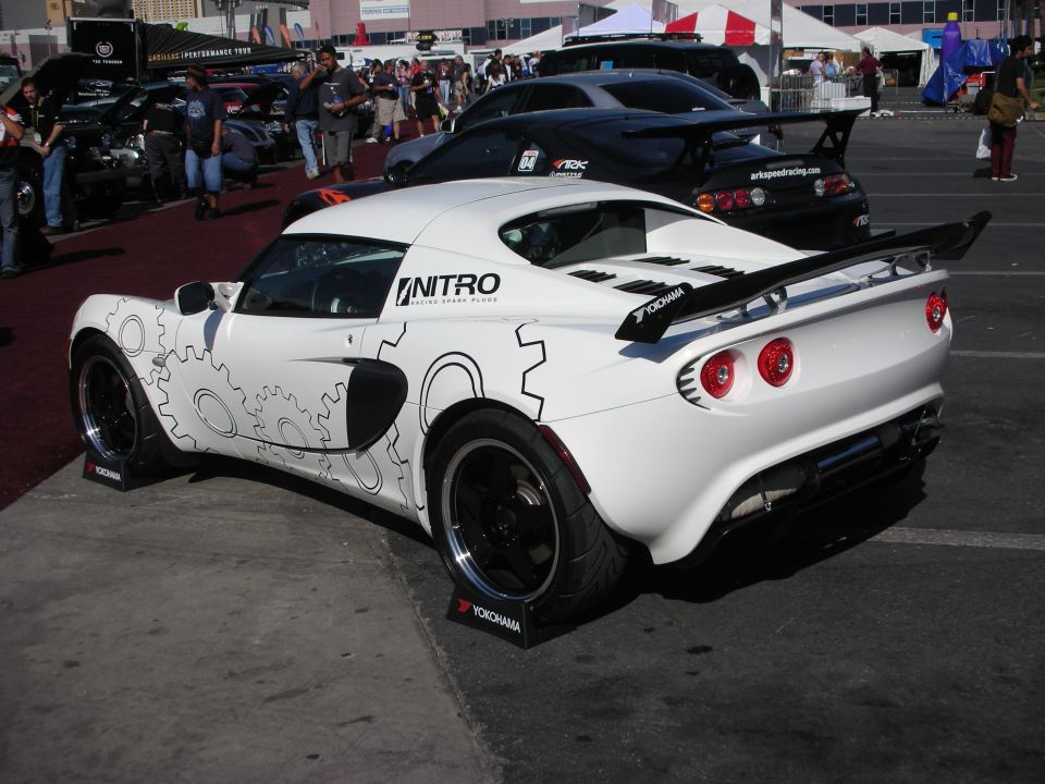 White Lotus sports car with cog graphics and rear wing in a show lot