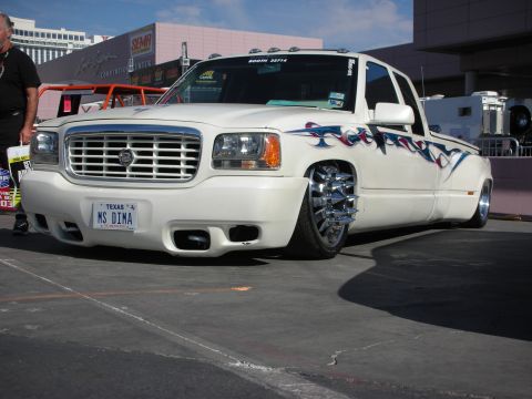 1998 Ford Crown Victoria - white lowered Chevrolet dually pickup with flame graphics wears chrome wheels and a Texas license plate at a show.
