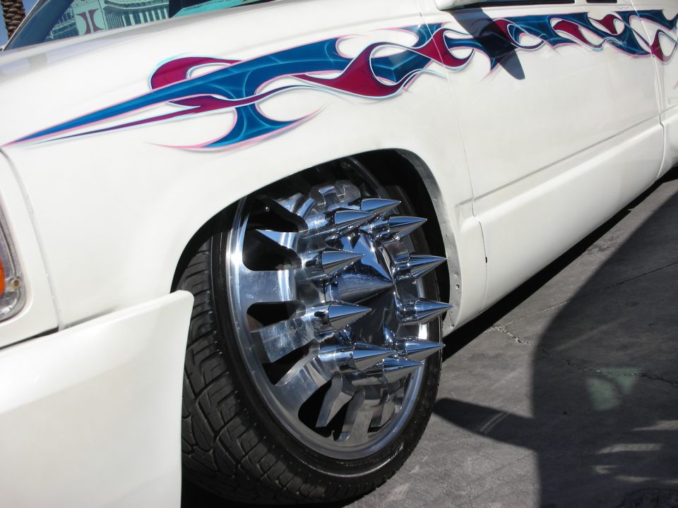 Chrome dually wheel with spiked lug caps on a white flamed pickup