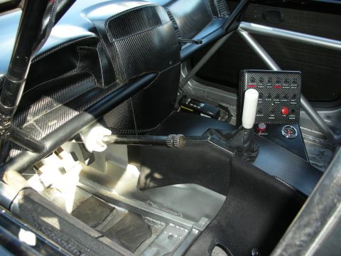 1998 Ford Crown Victoria - stripped race car interior shows a roll cage, carbon-fiber panels, a center shifter, and a switch panel.